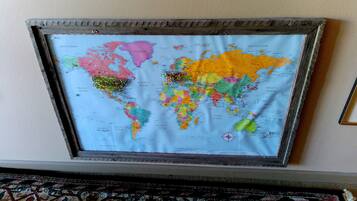 A framed world map with a compass rose, mounted on a wall.