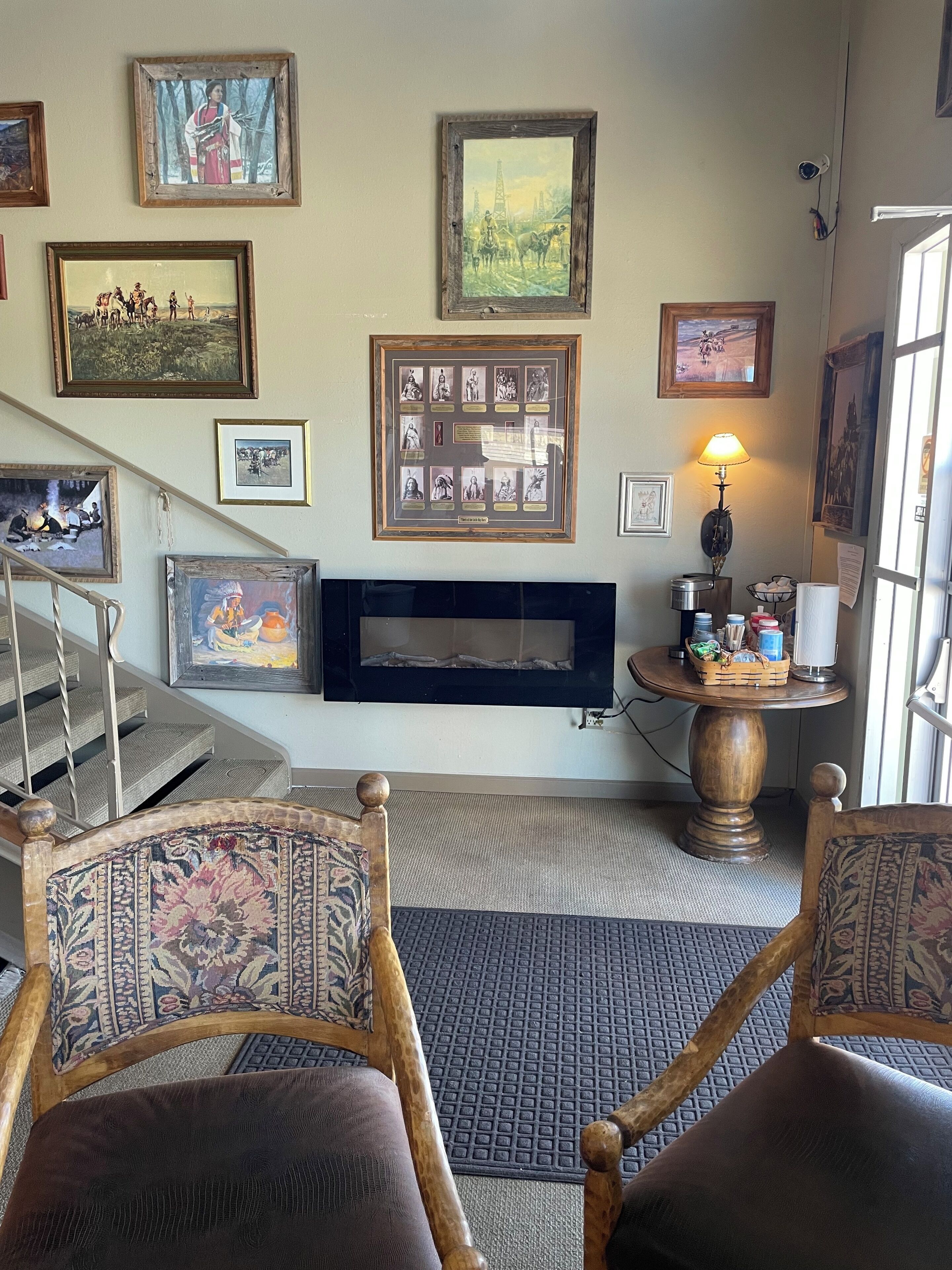 Una sala de estar con chimenea, obras de arte enmarcadas en las paredes, un televisor y una escalera.