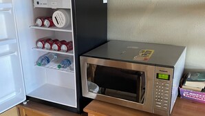 A compact kitchenette with a refrigerator, microwave, and a small wooden table. - Rawlins Lodge (Rawlins)