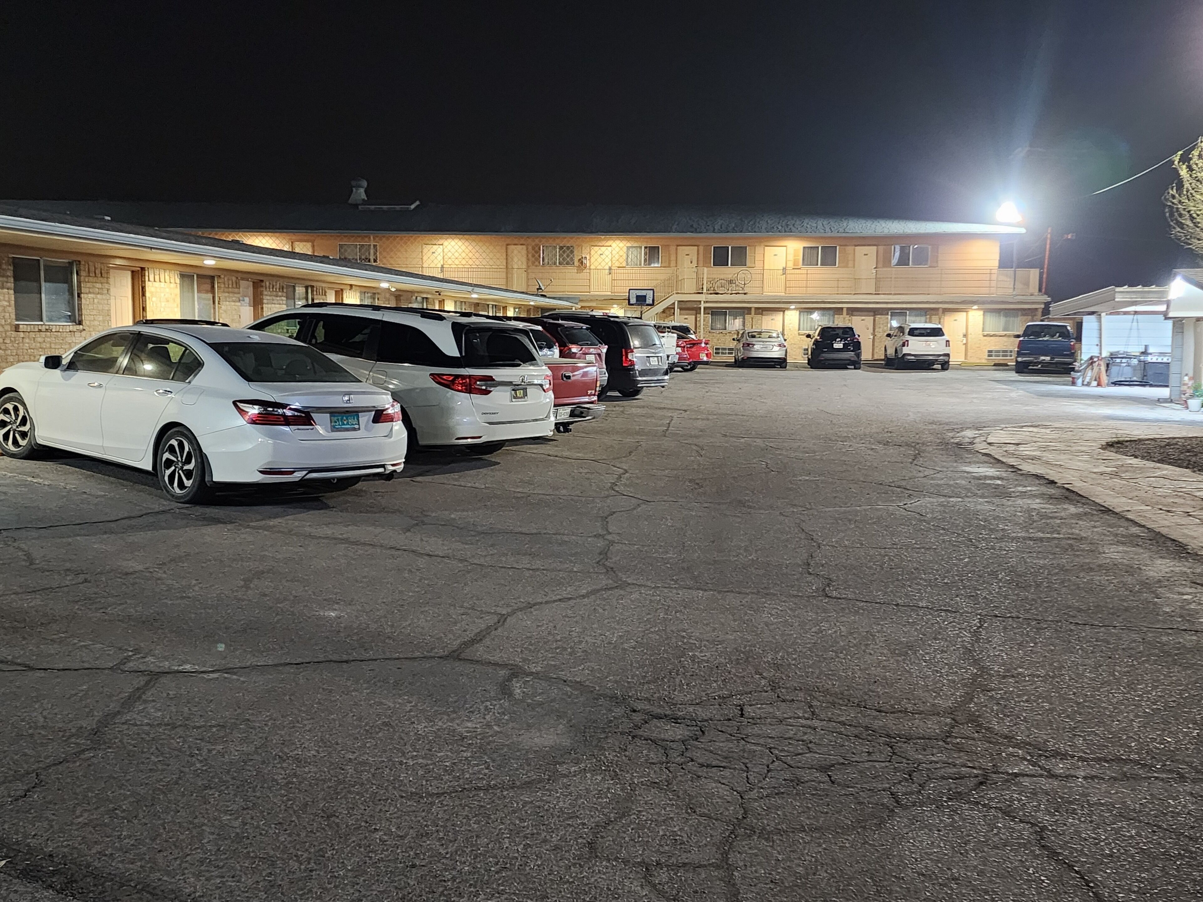 A parking lot with several cars parked in front of a building with multiple windows and a flat roof.