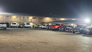 A parking lot with several vehicles, including trucks and cars, and a building with multiple windows and a staircase.