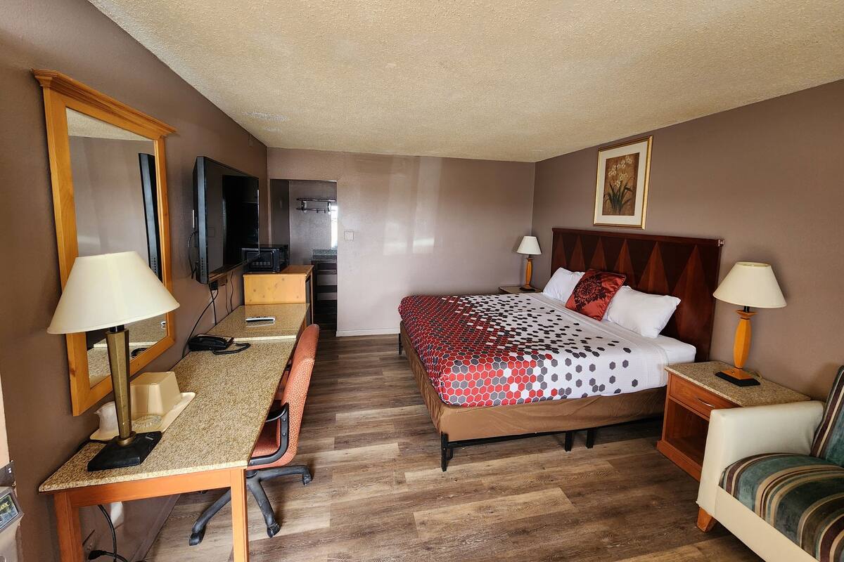 A hotel room with a bed, desk, chair, and a television.