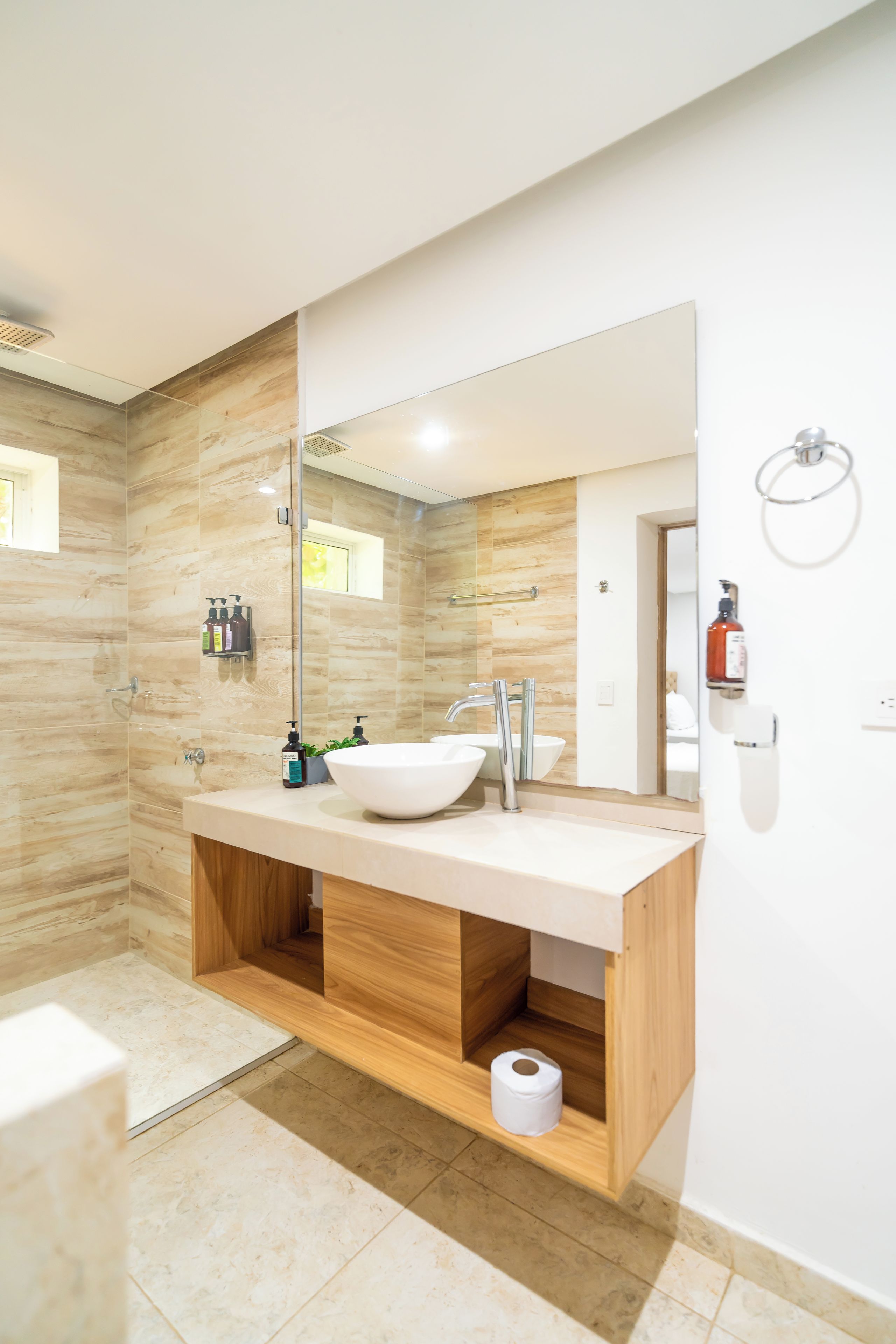 A modern bathroom with a large mirror, a white sink, and a shower area.