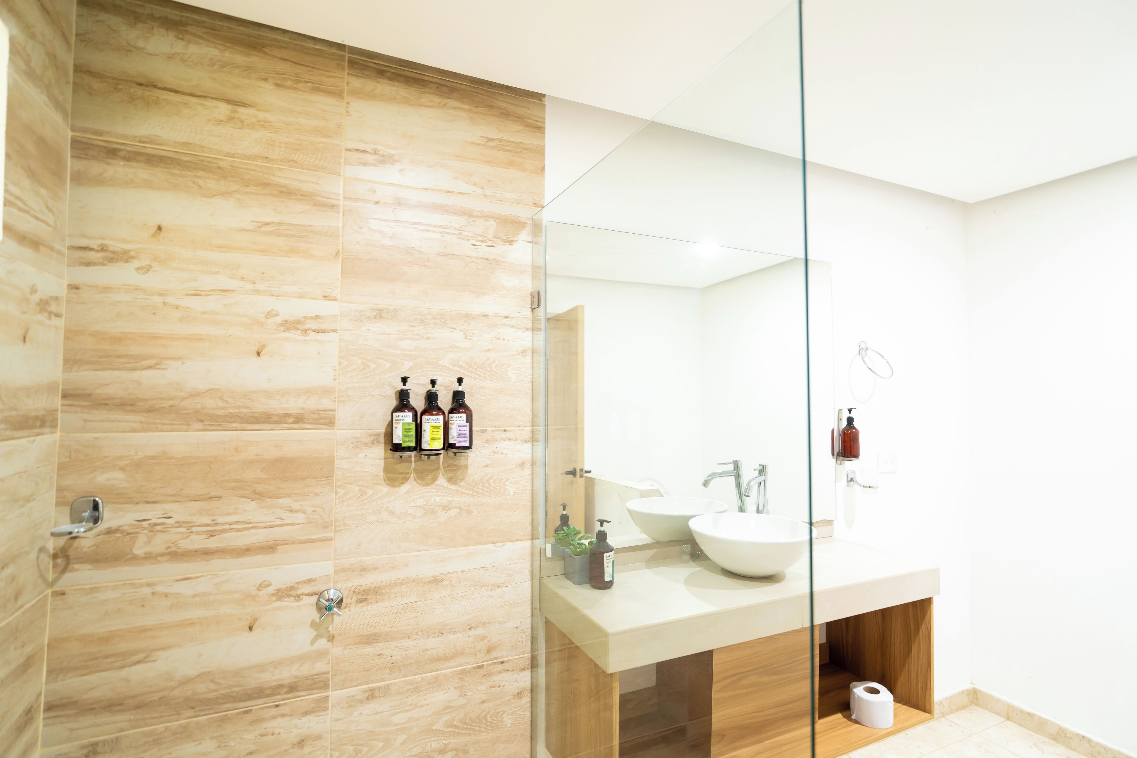 A modern bathroom with a glass shower enclosure, a wooden vanity, and a large mirror.