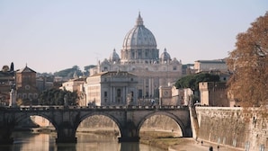 A bridge over a river with a large domed building in the background. - Maison Candia Luxury House (Rome)
