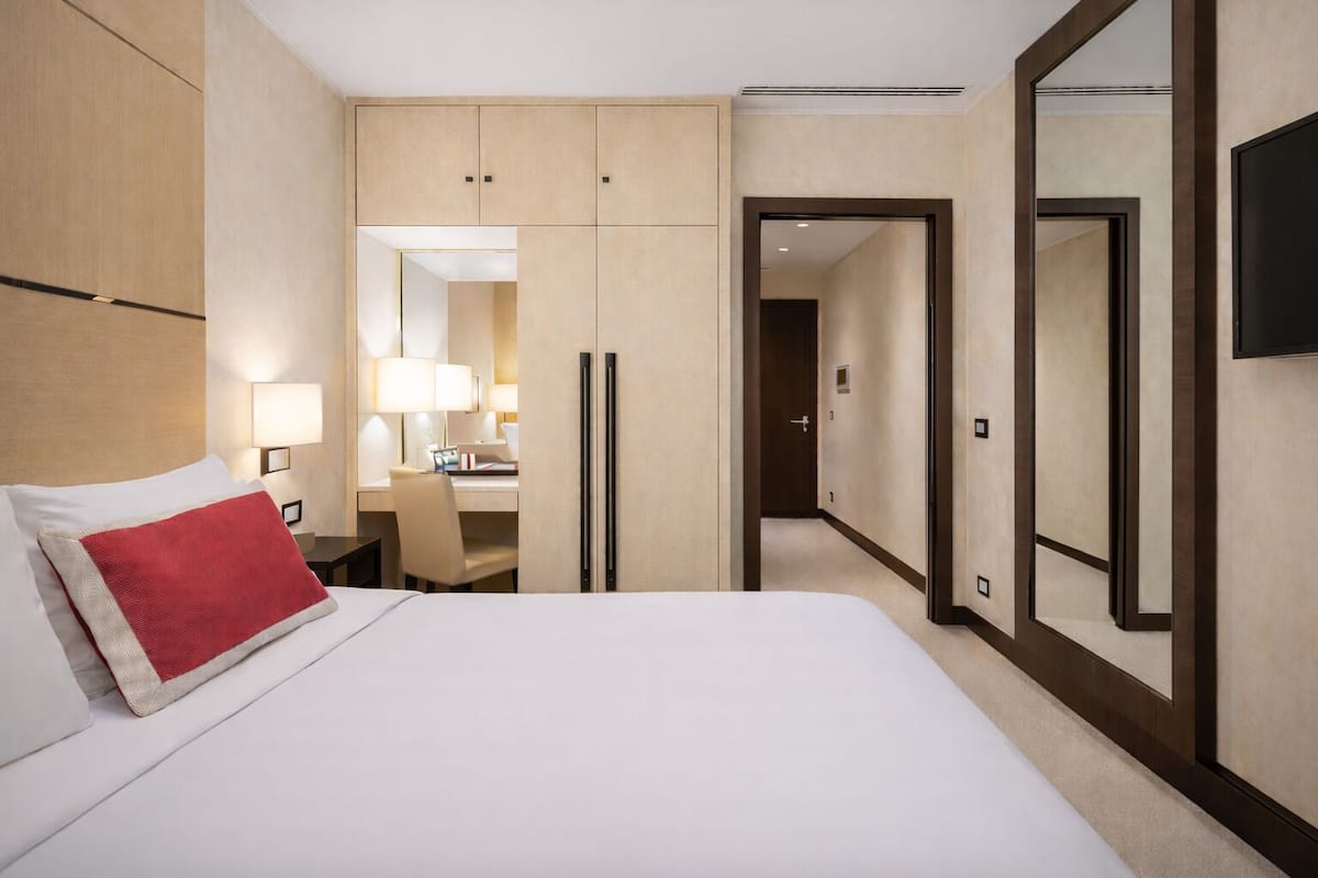 Una camera d'albergo con un letto, una scrivania con una sedia, uno specchio e un armadio.