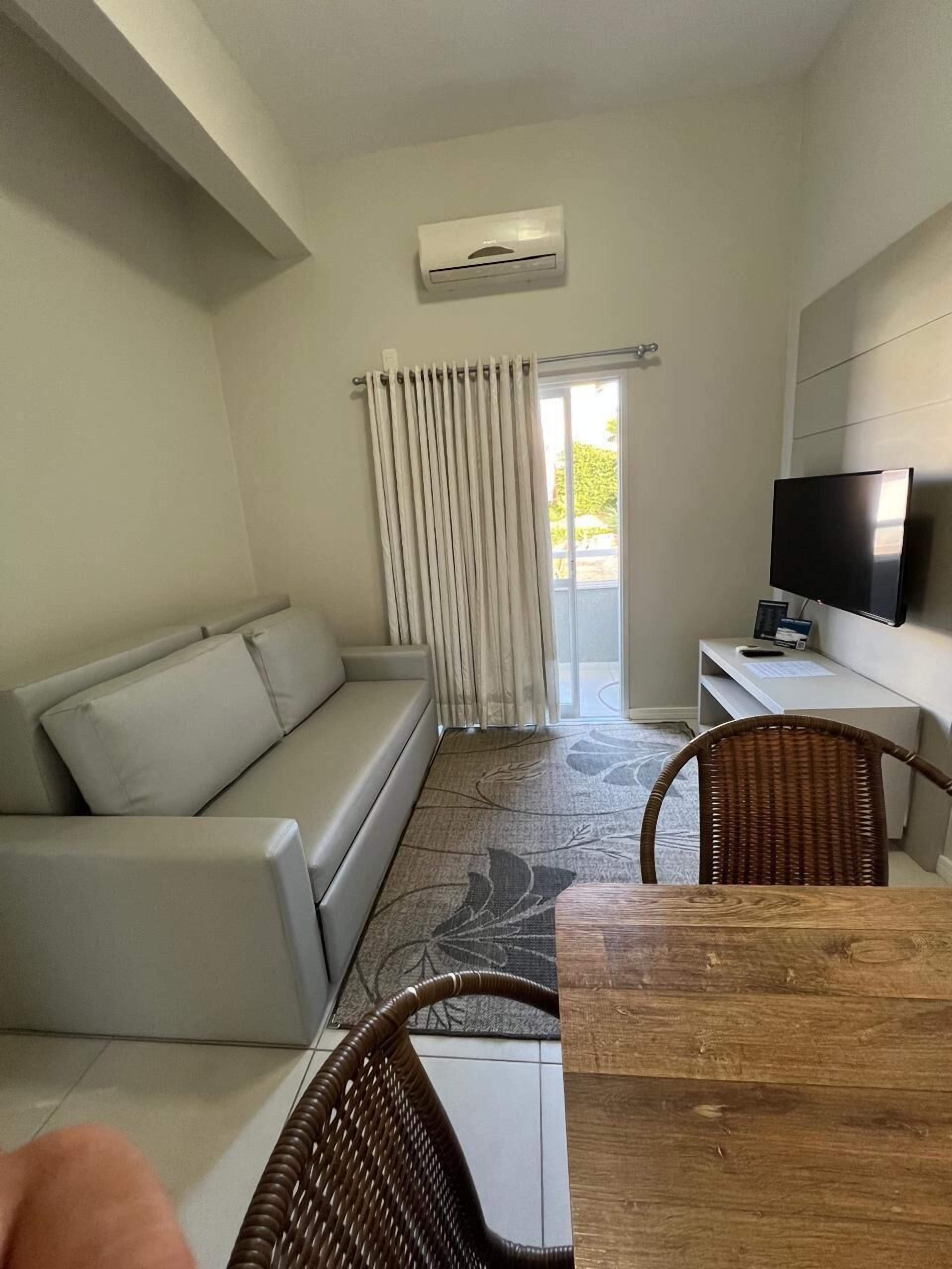 A modern living room with a sofa, a dining table, and a TV.