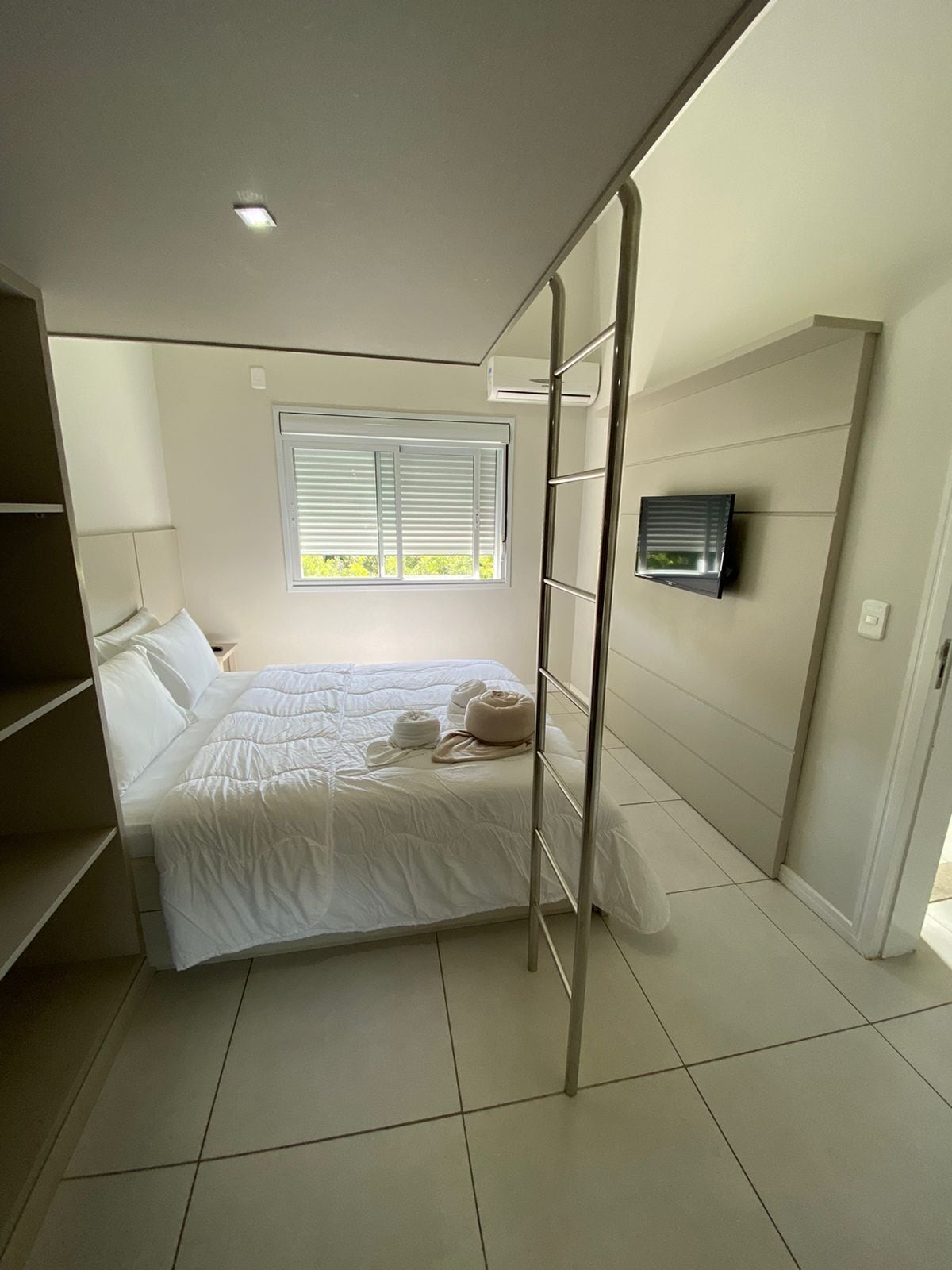 Une chambre à coucher avec un lit, une fenêtre, une télévision et une armoire.