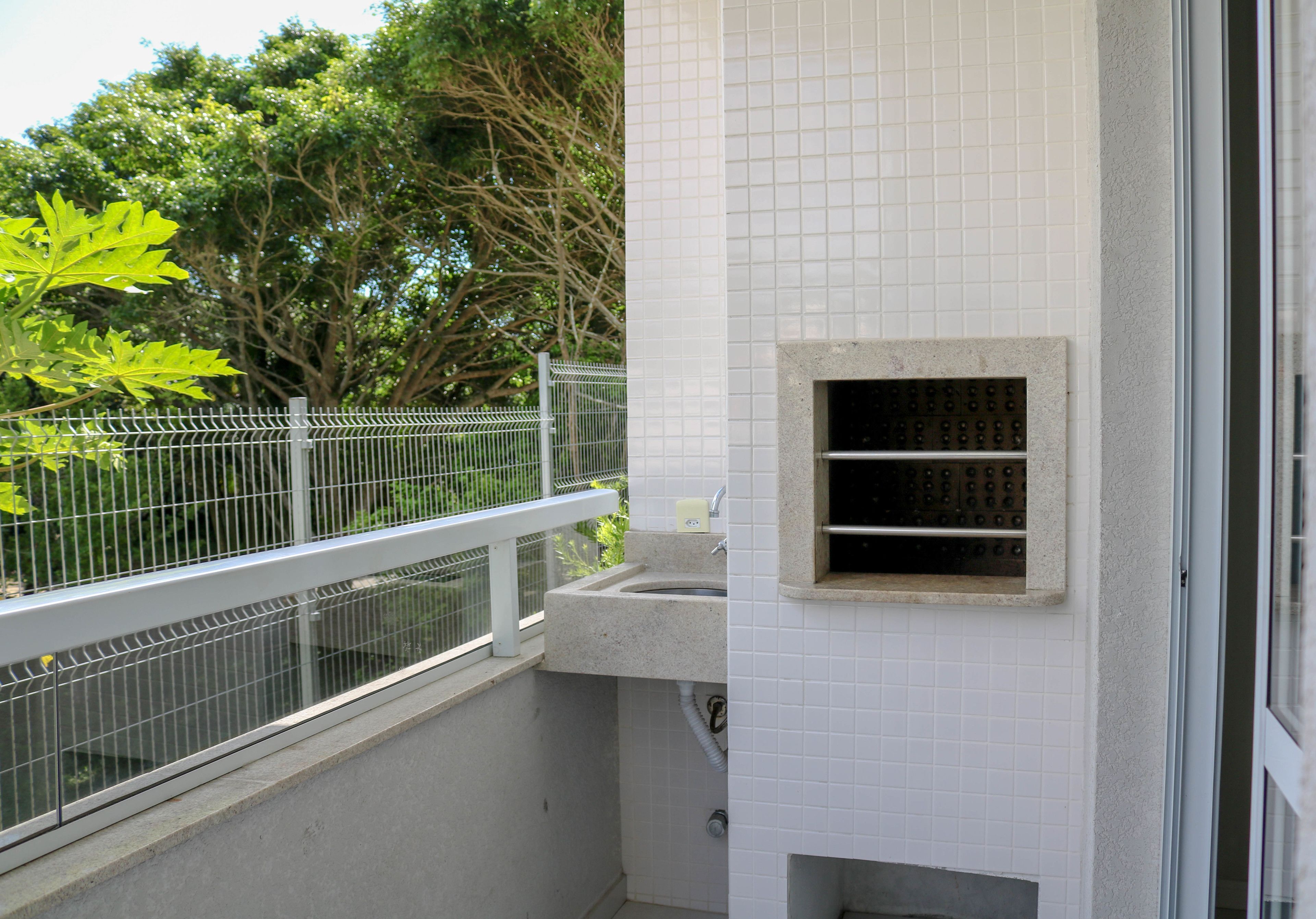 A bathroom with a sink, a small window, and a tiled wall.