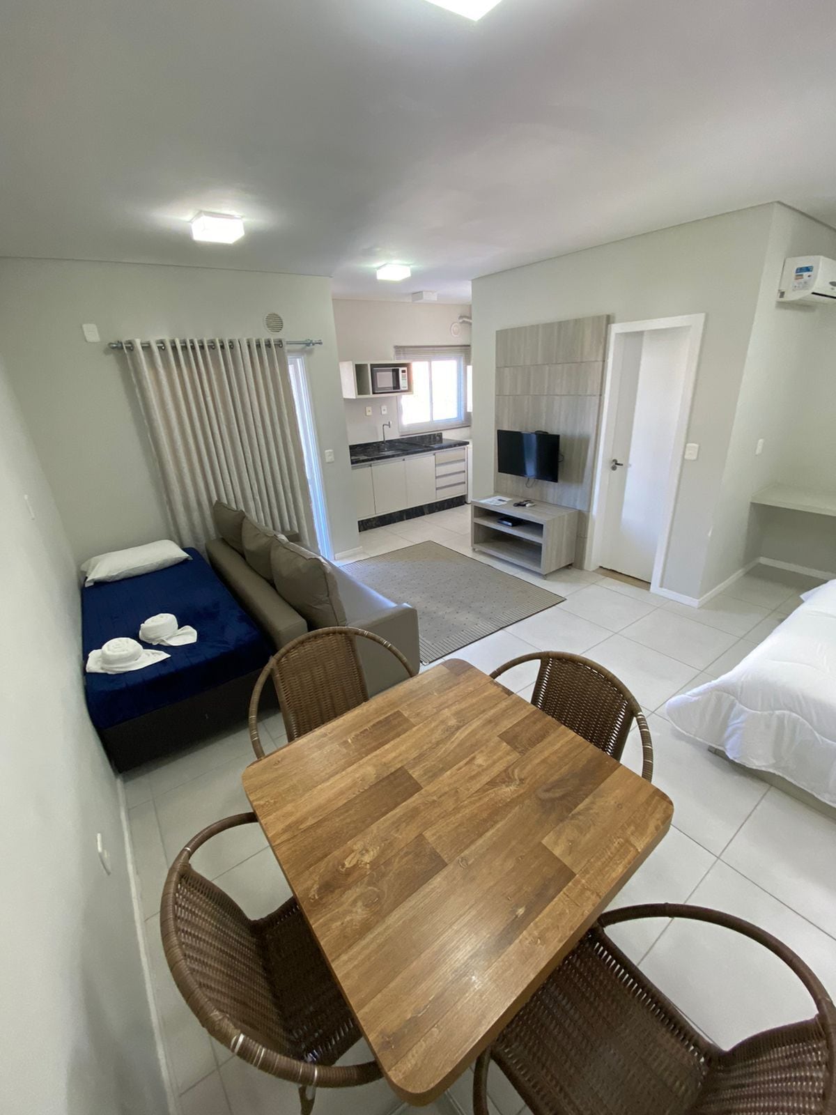 Un espacio habitable compacto con kitchenette, comedor y dormitorio.