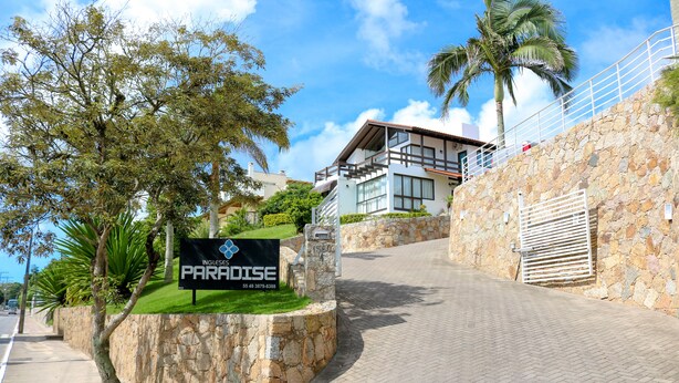 A stone wall with a sign for Paradise Resort.