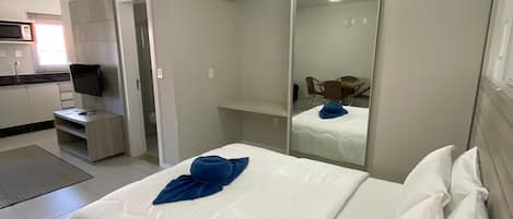 A hotel room with a bed, a wardrobe, a mirror, and a kitchenette.
