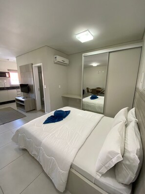A hotel room with a bed, a mirror, a wardrobe, and a kitchenette. - Ingleses Paradise (Florianópolis)