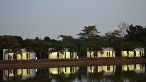 Une rangée de chalets à un seul étage, avec une étendue d'eau qui reflète la lumière au premier plan.