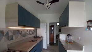 Une cuisine avec des meubles de rangement bleus, une cuisinière à gaz, un four à micro-ondes et un réfrigérateur.