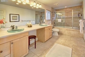 A modern bathroom with a glass-enclosed shower, a large mirror, and a vanity with a glass bowl sink. - Maui Garden Oasis (Lahaina)