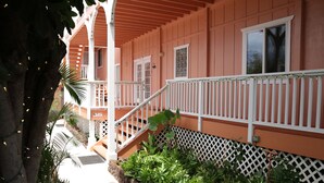 A pink building with white railings and a staircase leading to a porch. - Maui Garden Oasis (Lahaina)