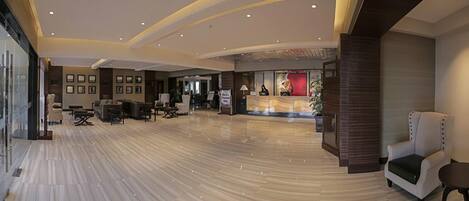 A spacious lobby with a reception desk, seating area, and framed pictures on the walls.