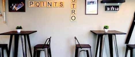 A cafe interior with wooden tables, black chairs, and a wall displaying 'TREE POINTS BISTRO' signs.