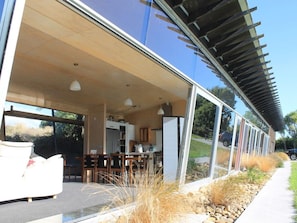 A modern house with a large glass door leading to a dining area and kitchen.