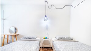 Quarto com duas camas, uma mesa pequena e um espelho, além de um lustre.