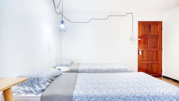 Quarto com duas camas, uma porta de madeira e uma luminária singular.