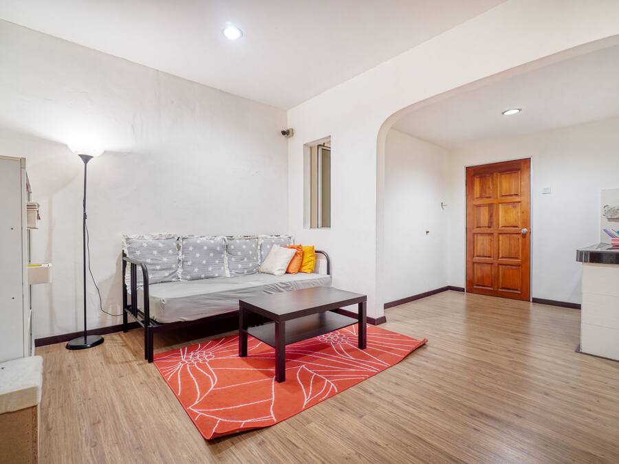 Una sala de estar con sofá, mesa de centro, lámpara y suelo de madera.