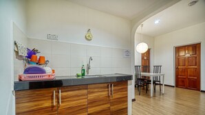Uma cozinha com armário de madeira, pia e área de refeições com cadeiras e mesa.