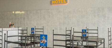A N1 Hotel dining area with multiple tables and chairs, a signboard, and a tiled wall.