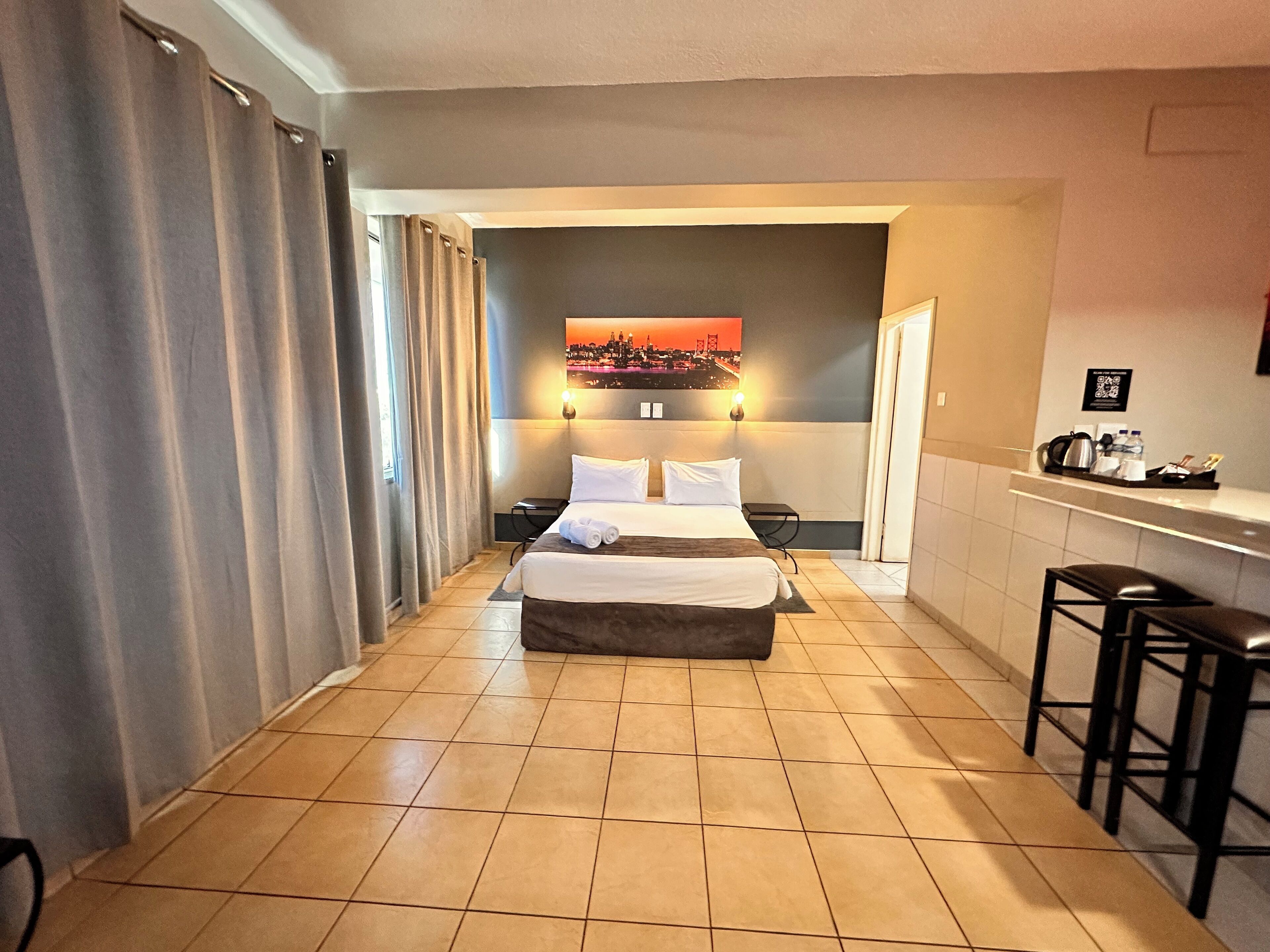 Une chambre d’hôtel avec un lit, un bureau, une chaise et un tableau au mur.