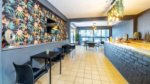 Een modern restaurantinterieur met een metselwerk toonbank, zwarte stoelen en een wand met tropische bloemen.