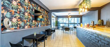 Ein modernes Restaurant mit einer Ziegel-Theke, schwarzen Stühlen und einer Wand mit tropischen Blumen.