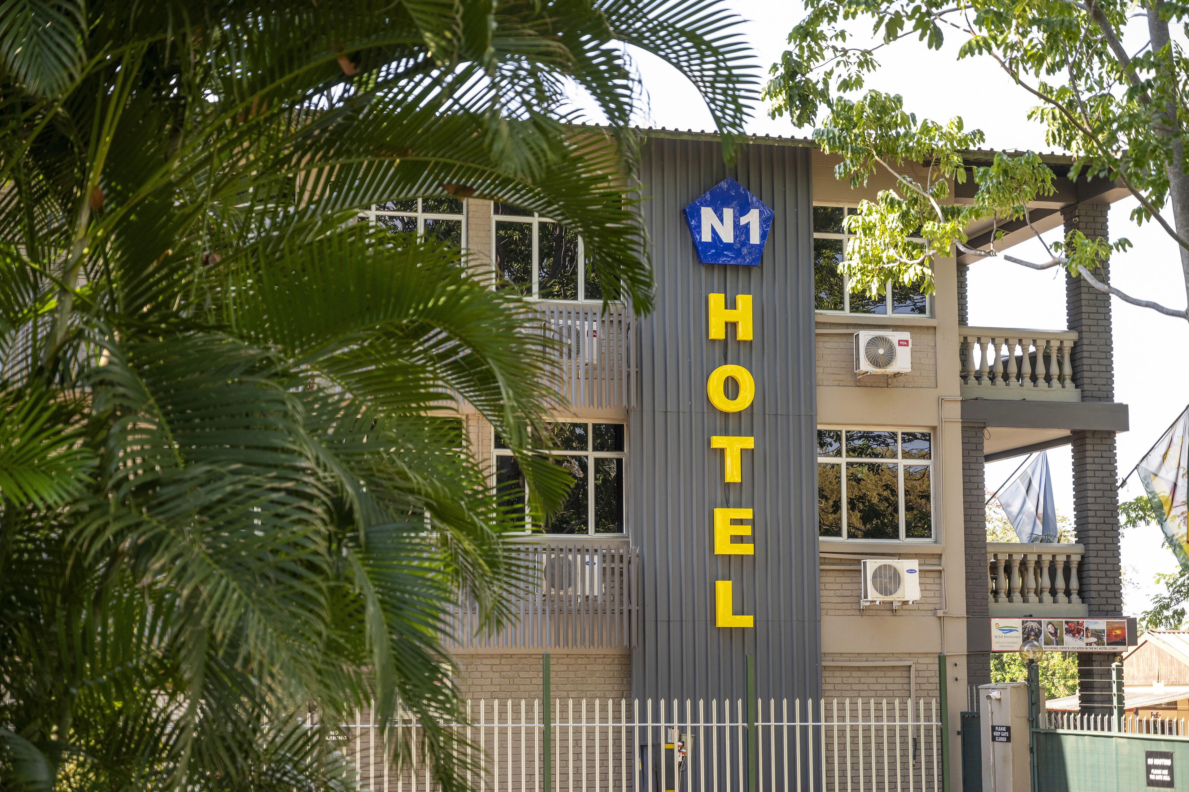 A hotel with a prominent 'N1 HOTEL' sign, a balcony, and an air conditioning unit.