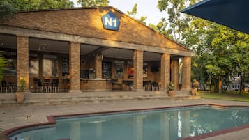 Una piscina al aire libre, sombrillas, sillones reclinables de piscina