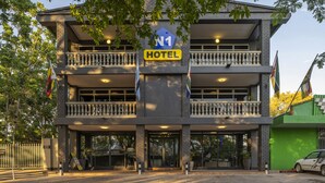 Een hotel met een bord dat aangeeft dat het aan de N1 route ligt, met een gebouw van twee verdiepingen, balkons en een hekwerk.