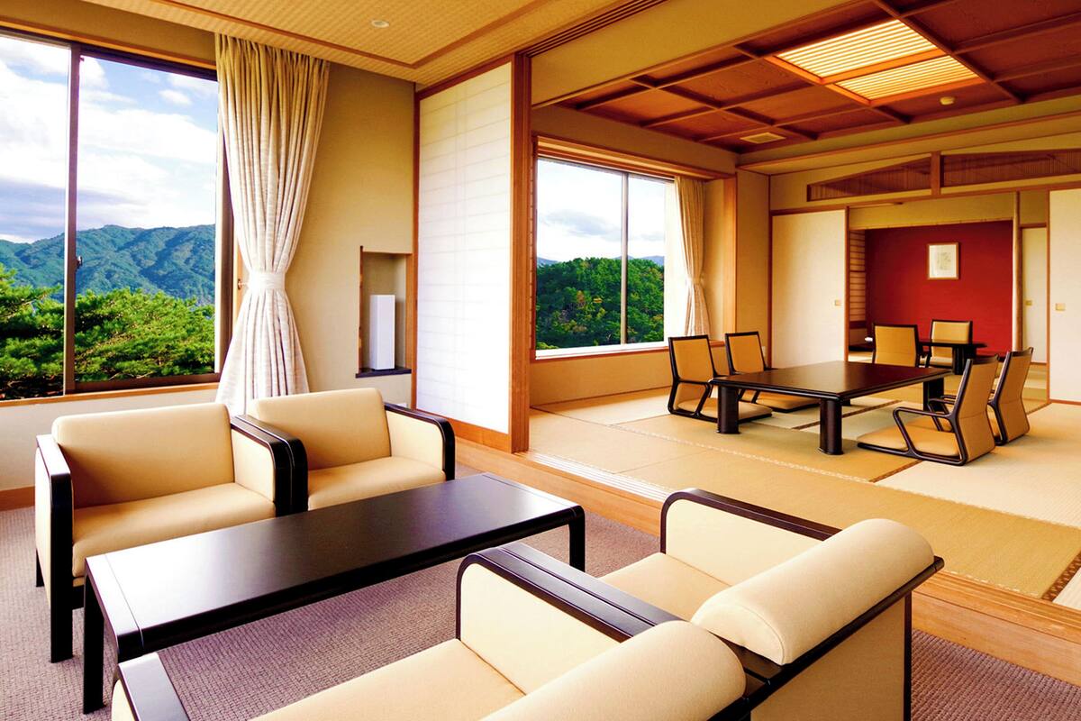 A spacious room with a large table and chairs, a sofa, and a view of mountains through large windows.