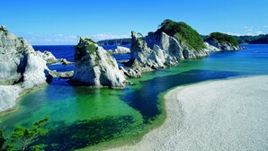 Un paisaje costero con formaciones rocosas, agua cristalina y una playa arenosa.