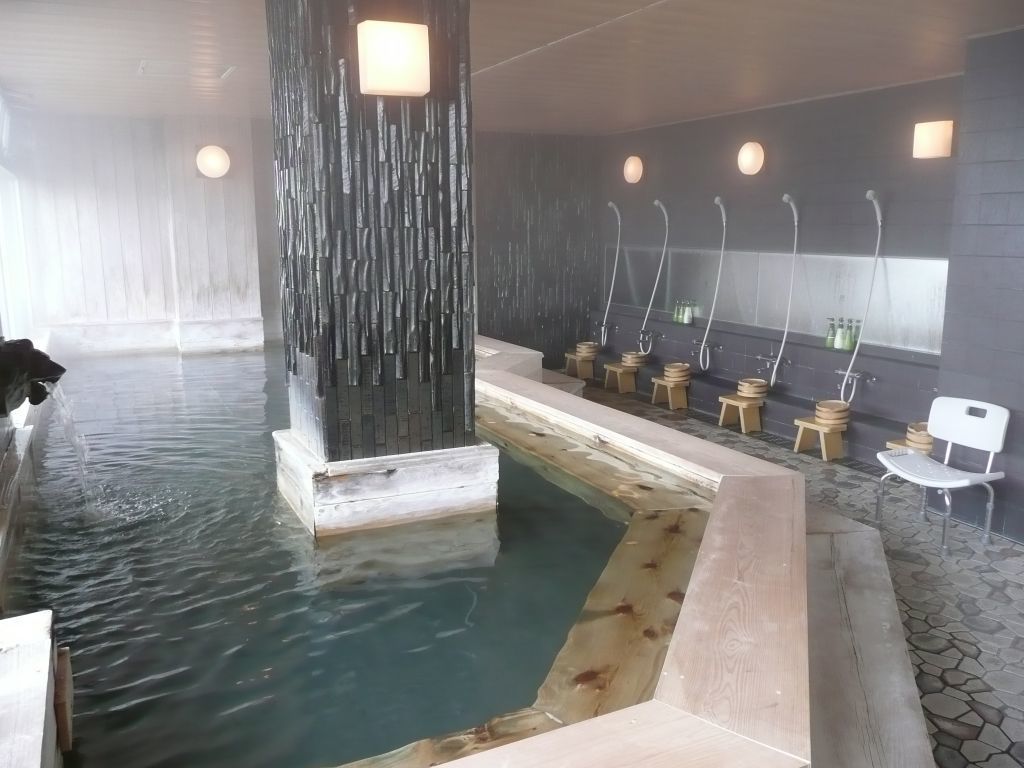 Un espace spa doté d’une grande piscine, de tabourets en bois et d’un mur agrémenté d’éléments d’eau.