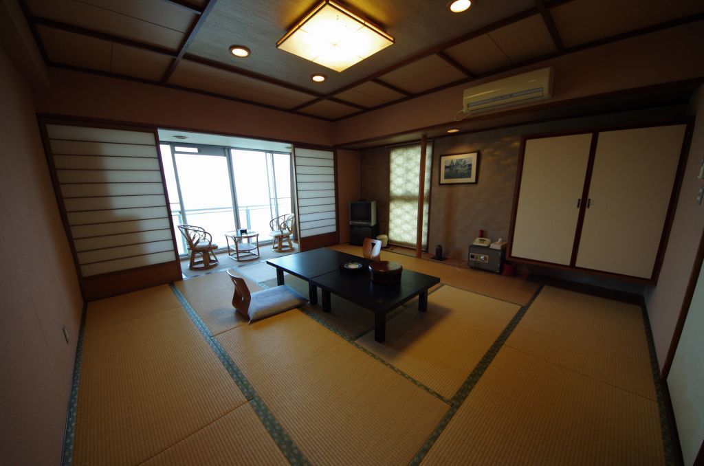 A traditional Japanese room with tatami flooring, a low table, and sliding doors.