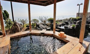 A hot spring area with a wooden deck, a stone bench, and a view of the sea. - Donkairo (Ako)