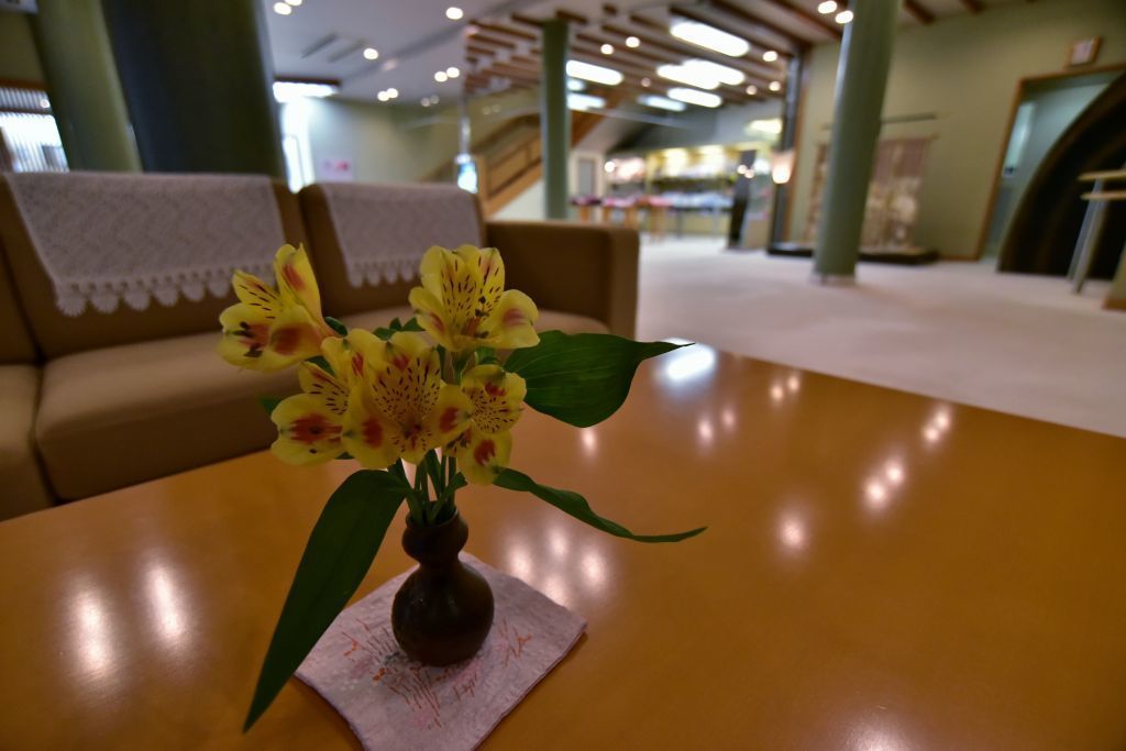 Une table en bois sur laquelle est posé un vase rempli de fleurs jaunes.
