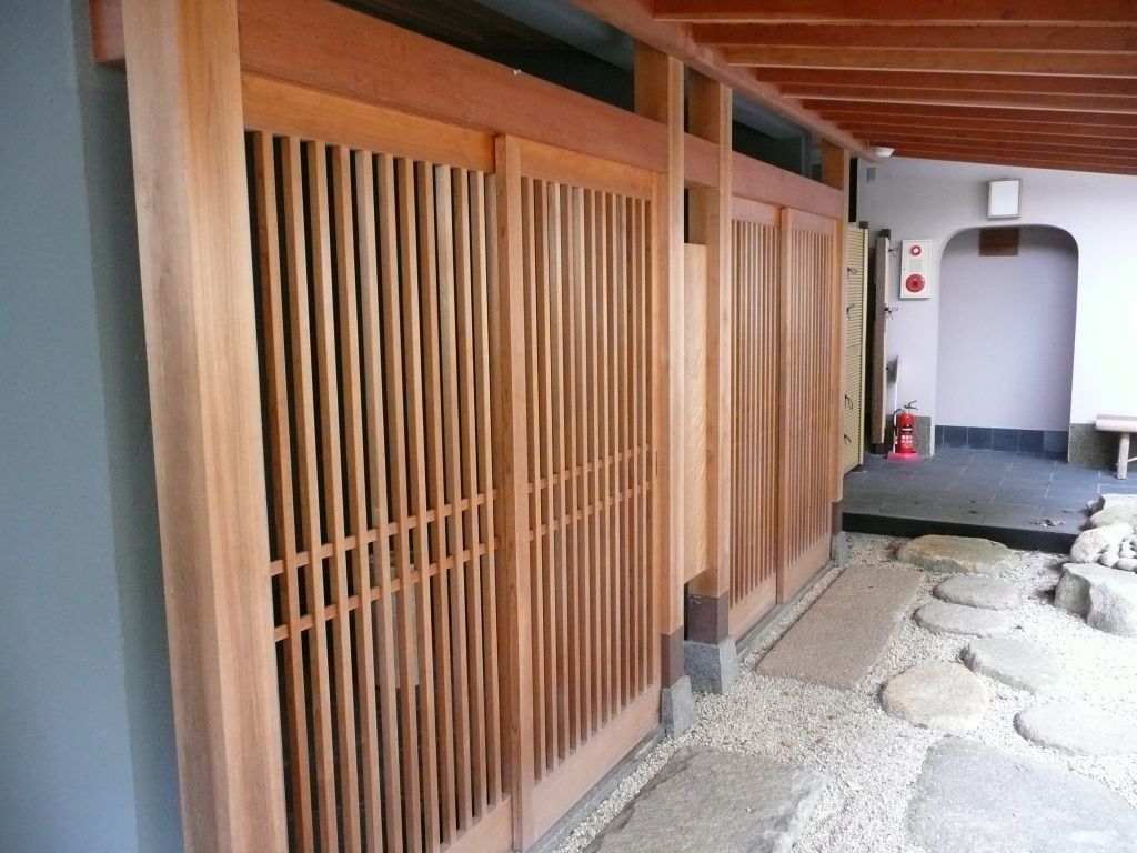 A traditional Japanese-style building with wooden sliding doors and a stone pathway leading to a door.