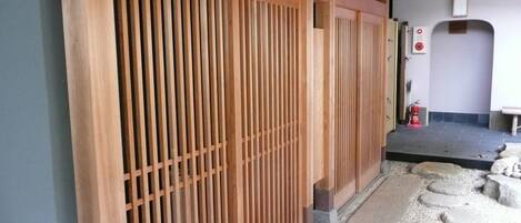 A traditional Japanese-style building with wooden sliding doors and a stone pathway leading to a door.