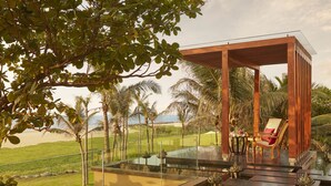 A modern outdoor lounge area with a glass balustrade overlooking a pool and a beach. - Sentido Heritance Negombo (Negombo)