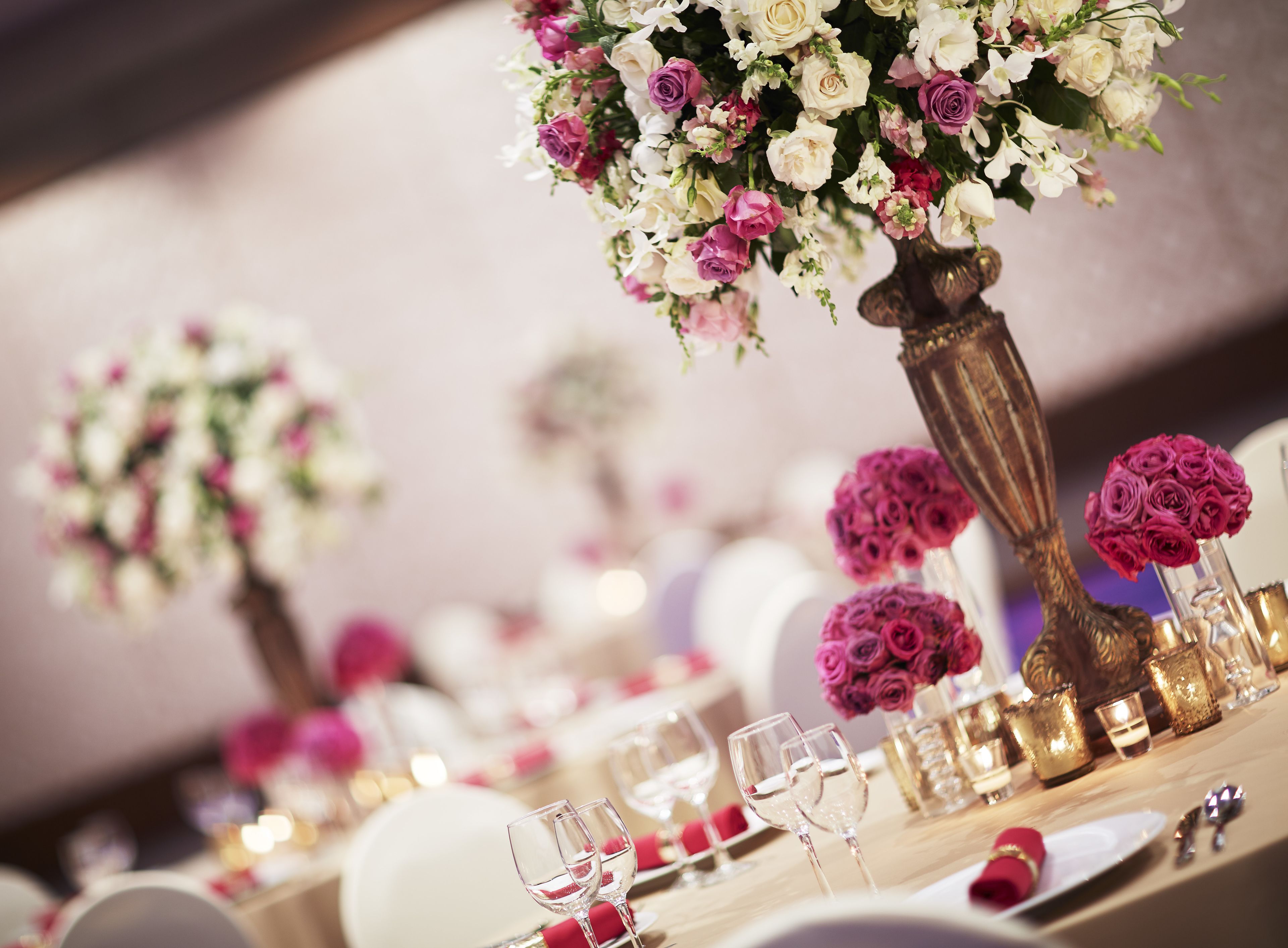 A table set for a formal event with floral centerpieces, wine glasses, and elegant tableware.