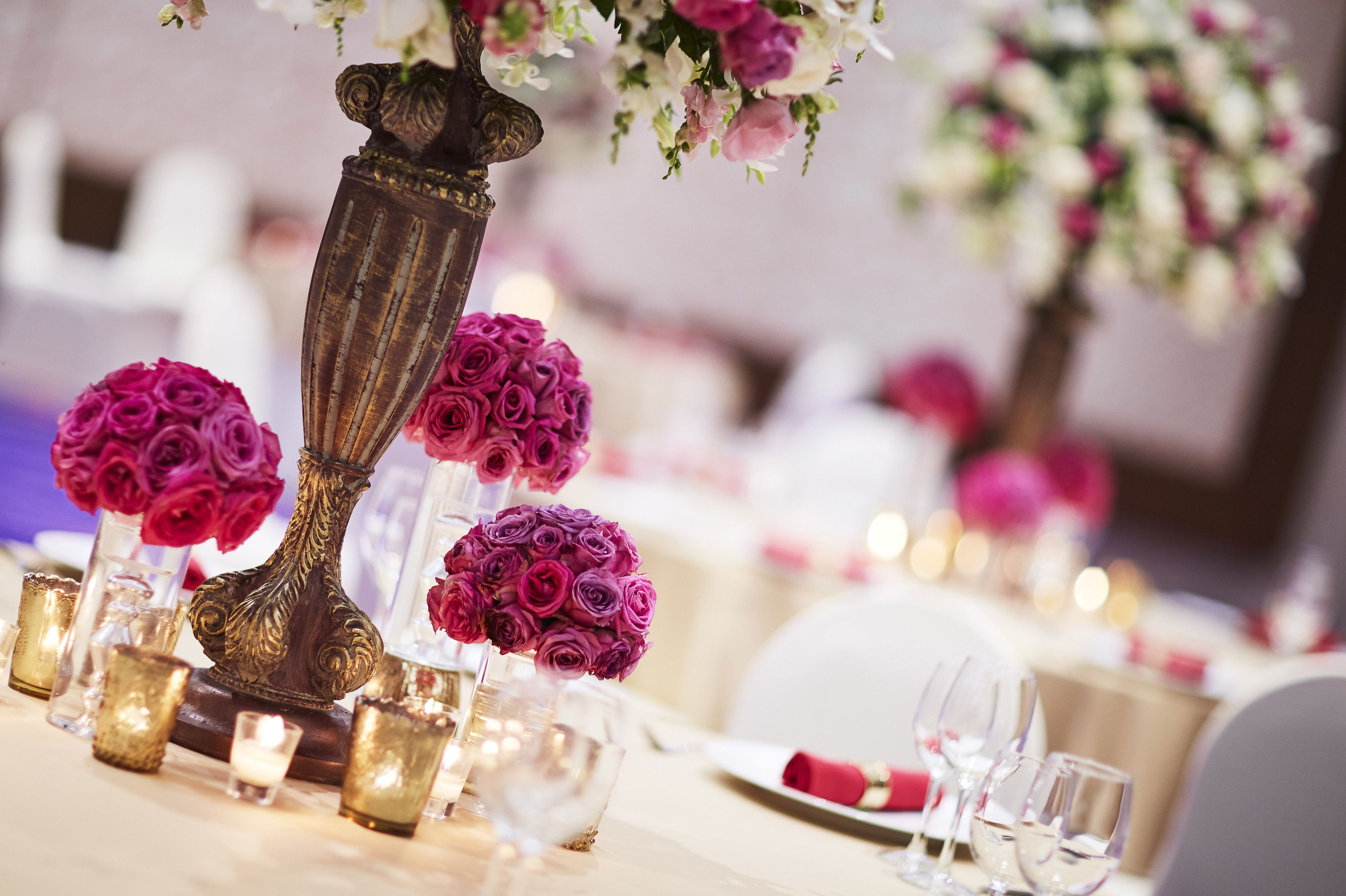 Mesa posta com elegante cristais, velas e um arranjo de rosas cor-de-rosa em um vaso decorativo.