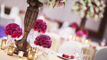 Mesa posta com elegante cristais, velas e um arranjo de rosas cor-de-rosa em um vaso decorativo.