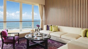 A hotel room with a large window overlooking the ocean, a sofa, a coffee table, and a ceiling fan. - Sentido Heritance Negombo (Negombo)