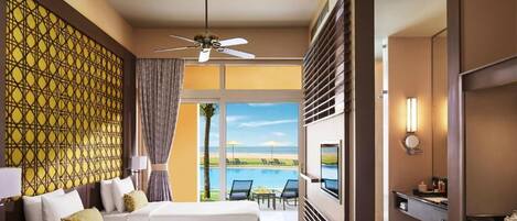 Habitación de hotel con dos camas, televisión, ventilador de techo y vista a una piscina y playa.