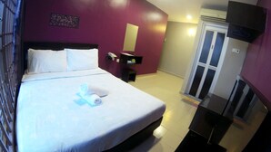 Une chambre d’hôtel avec un lit, un petit bureau, un miroir et une porte.